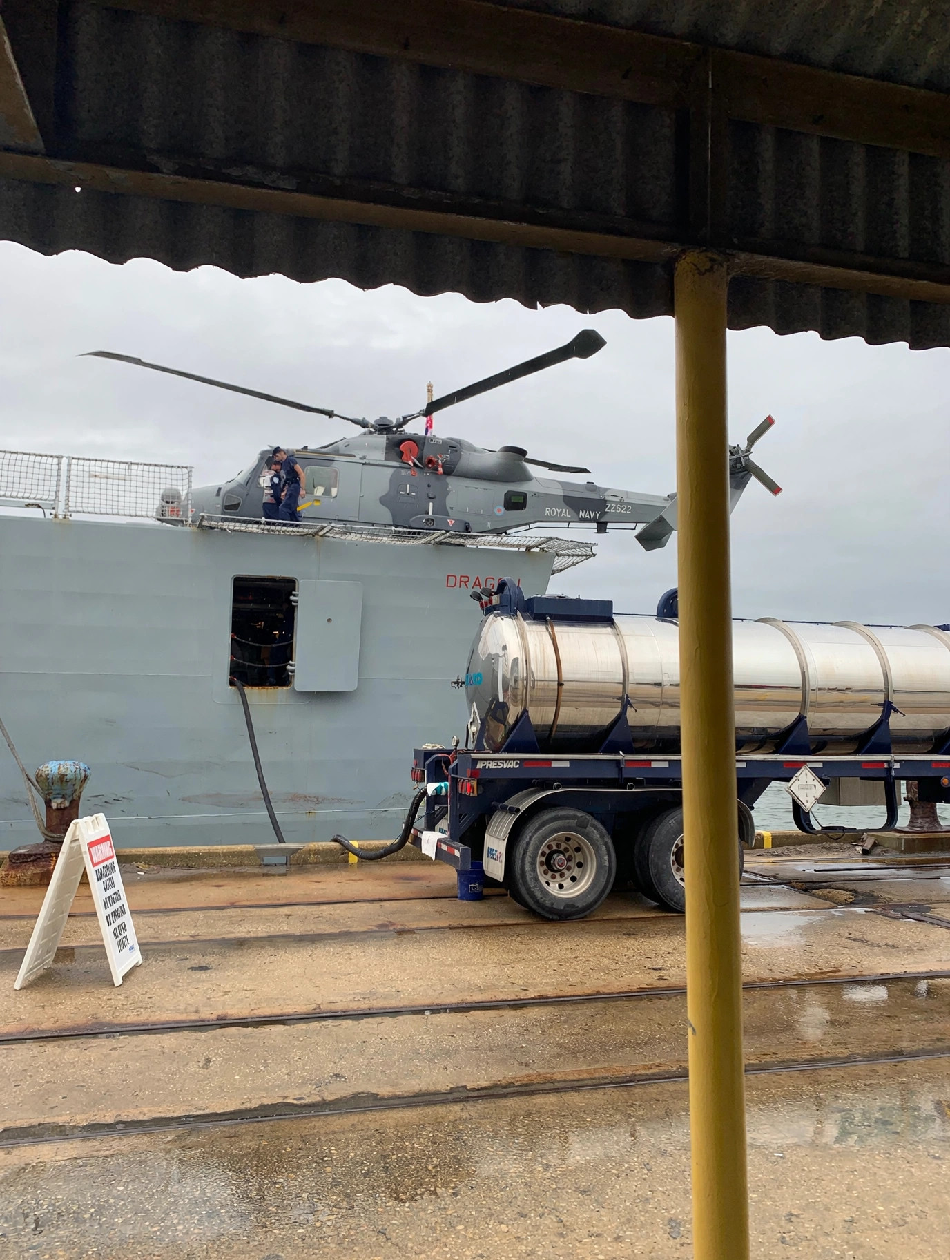 Tanker crew conducting a pierside transfer operation alongside a naval vessel